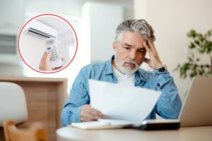 uomo disperato che legge bolletta e climatizzatore
